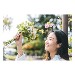 Portrait of a beautiful young woman against white flowering plants