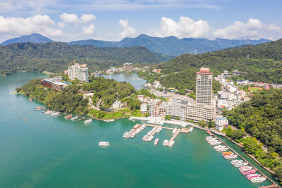 High angle view of city by sea and mountains against sky