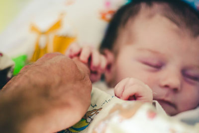 Close-up of new born baby holding finger while sleeping