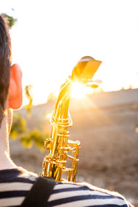 Midsection of man playing guitar against sky during sunset