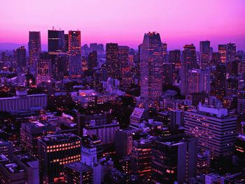 Illuminated buildings against purple sky in city at dusk