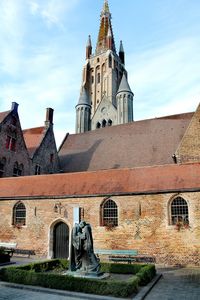 Low angle view of historic church of our lady and medieval buildings in brugge. 