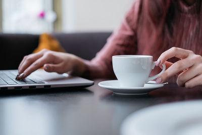 Midsection of man holding coffee cup on table