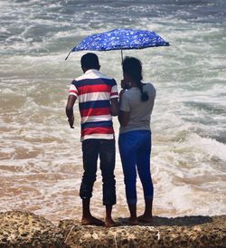 Rear view of friends standing on beach