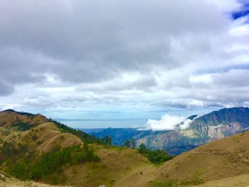 Scenic view of mountain range against cloudy sky