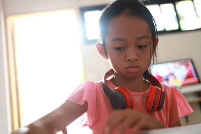 Close-up of girl wearing headphones while sitting at home