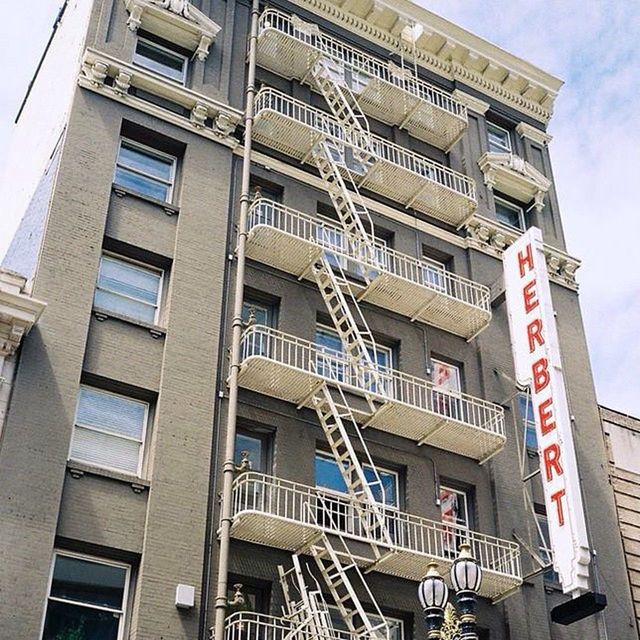 architecture, low angle view, building exterior, built structure, building, city, window, residential building, sky, day, outdoors, residential structure, western script, modern, text, no people, communication, office building, city life, fire escape