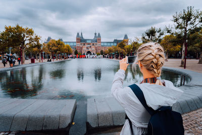 Woman tourist taking photo of the rijksmuseum in amsterdam on the mobile phone. travel in europe