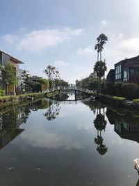 Reflection of trees and swimming pool in lake against sky