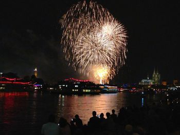 Firework display over river against sky at night