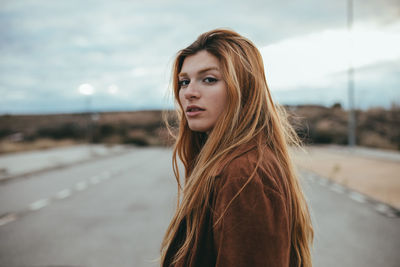 Portrait of beautiful young woman standing against sky