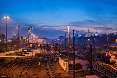 Illuminated railroad tracks against sky at night in city