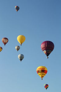 Low angle view of hot air balloons flying against clear sky