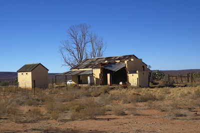 Houses on field against clear blue sky