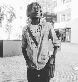 Portrait of young man standing on street in city