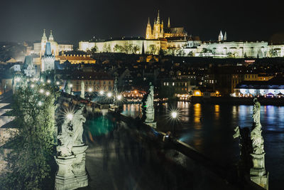 Illuminated bridge over river in city at night
