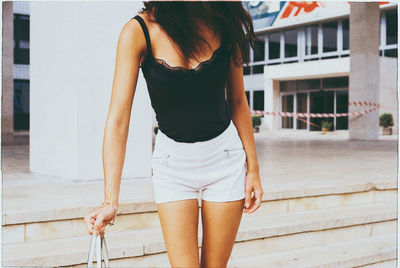 Midsection of young woman standing on steps