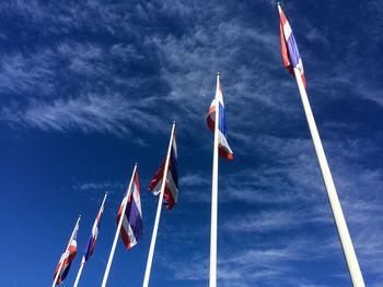 Low angle view of thai flags against sky