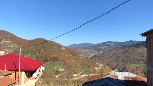 Scenic view of houses and mountains against clear blue sky