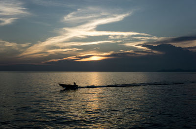 Silhouette man in sea against sky during sunset