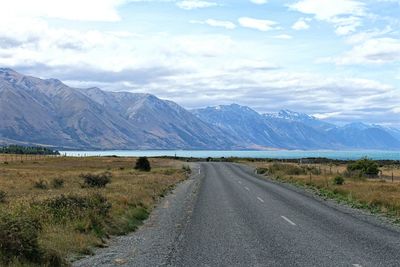 Road leading towards mountains against sky