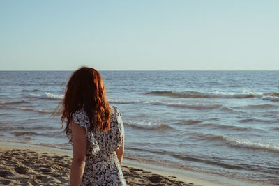 Rear view of woman standing at beach