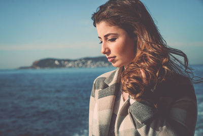 Close-up of young woman standing by sea against clear sky