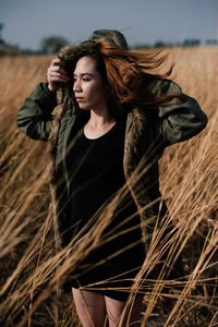 Young woman wearing hooded jacket amidst plants on field