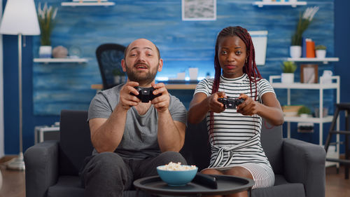 Portrait of friends playing video game at home