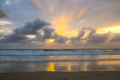 Scenic view of sea against dramatic sky during sunset