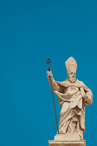 Low angle view of statue against blue sky