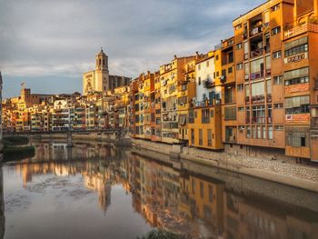 Buildings by river against sky at dusk