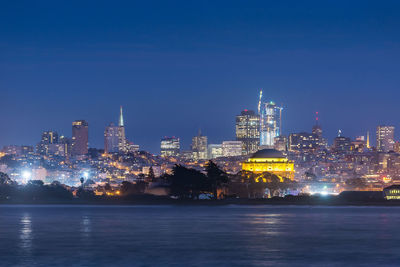 Illuminated buildings in city against sky at night