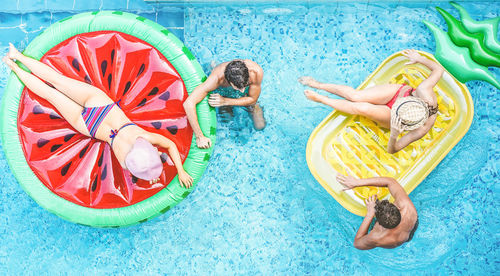 High angle view of friends with inflatable rings in swimming pool