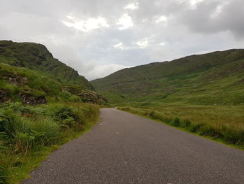 Road amidst green landscape against sky