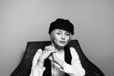 Portrait of young woman wearing hat against white background