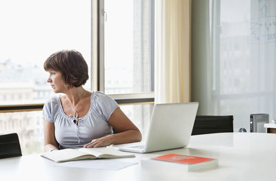 Mature woman looking out from office window