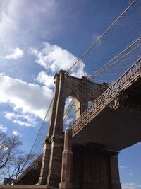 Low angle view of suspension bridge against cloudy sky