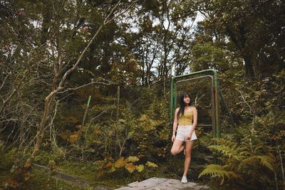Woman standing by tree in forest