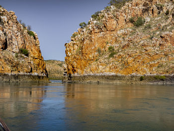 Rock formations in water against sky