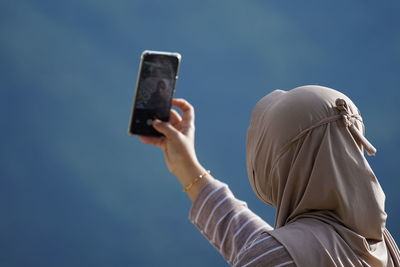 Low angle view of woman using mobile phone against sky