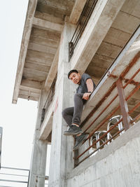 Full length portrait of young man standing against ladder