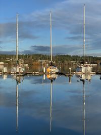 Sailboats moored in lake against sky
