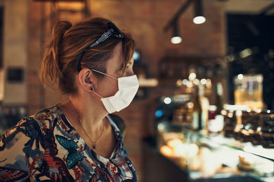 Woman wearing flu mask standing in cafe