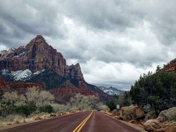 Road leading towards mountains against sky