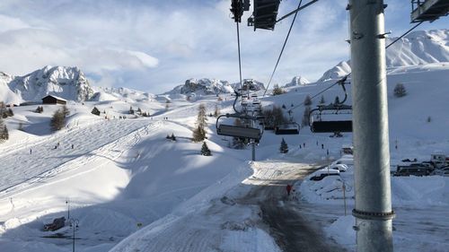 View of ski lift over snowcapped mountains against sky