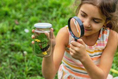 Smiling girl looking at butterfly through magnifying glass