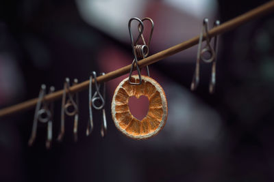 Close-up of heart shaped orange hanging on metal.