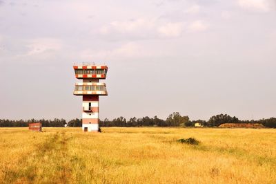 Lighthouse on field against sky