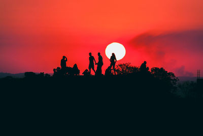 Silhouette people against orange sky during sunset